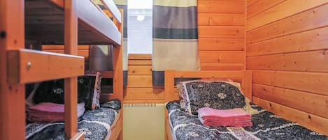 Una cabaña con dos literas, un ventanal con cortinas y un radiador.