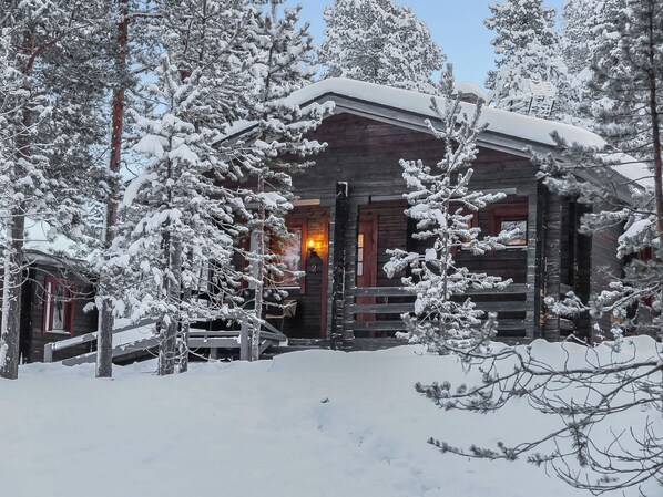 A log cabin surrounded by snow-covered trees.