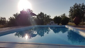 A rectangular swimming pool with a tiled edge, surrounded by a brick patio.