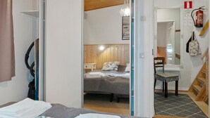 A hotel room with a bed, a bedside table, a chair, a mirror, a fire extinguisher, and a staircase. - Riekonraito a1 by Interhome (Inari)