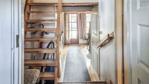 A narrow hallway with a wooden staircase leading to a loft area, a door to a room, and a window with curtains. - Riekonraito a1 by Interhome (Inari)
