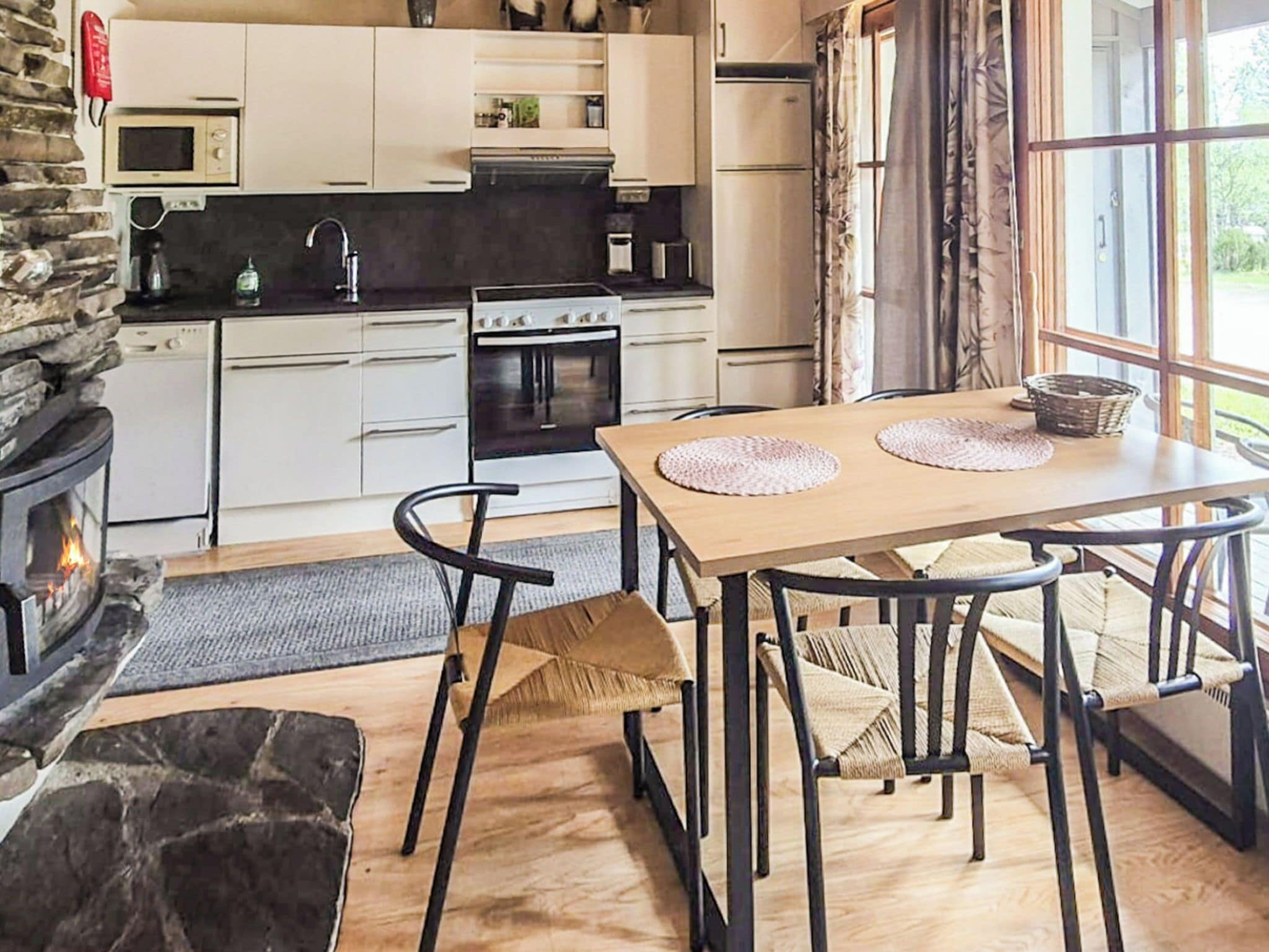 Una cucina moderna con mobili bianchi, un camino in pietra e un'area pranzo con tavolo e sedie in legno.