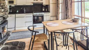 Una cucina moderna con mobili bianchi, un camino in pietra e un'area pranzo con tavolo e sedie in legno.