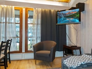 Relax in comfort with a view of the outdoors from the large window, featuring a comfortable armchair and flat-screen TV.