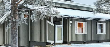 A single-story building with a metal exterior, a door labeled 'RIEKONRAITO,' and a small window with shutters.