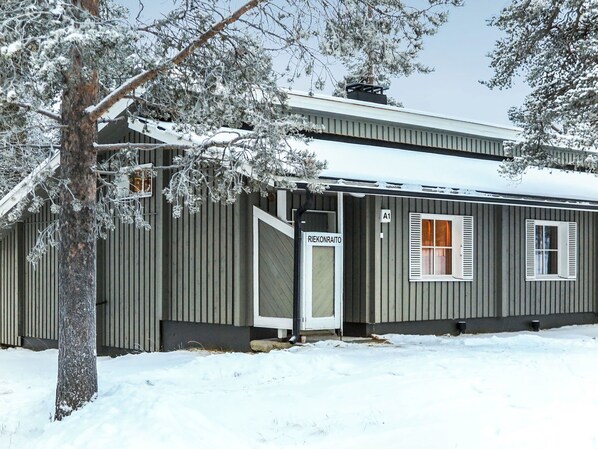 A single-story building with a metal exterior, a door labeled 'RIEKONRAITO,' and a small window with shutters. - Riekonraito a1 by Interhome (Inari)