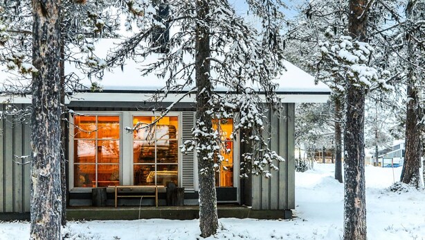A cabin with large windows and a bench outside, surrounded by snow-covered trees. - Riekonraito a1 by Interhome (Inari)