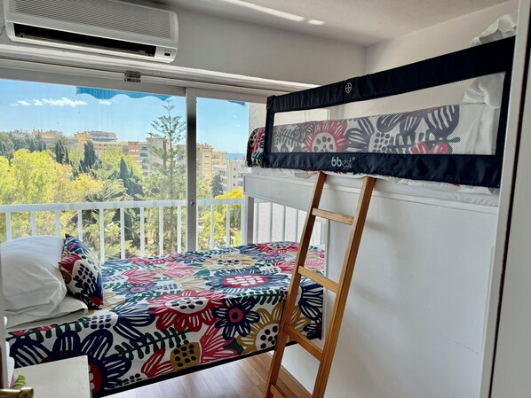 A balcony with a bed, a ladder, and an air conditioning unit.