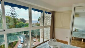 A hotel room with a large window offering a view of a road and greenery. - Skol Apartments Marbella beachfront, central with views and WIFI - 2 bedrooms (Marbella)