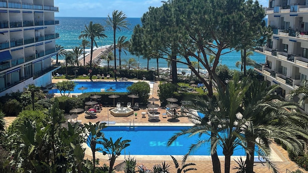 A resort with a pool, palm trees, and a view of the ocean. - Skol Apartments Marbella beachfront, central with views and WIFI - 2 bedrooms (Marbella)