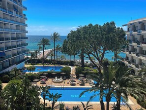 A resort with a pool, palm trees, and a view of the ocean.