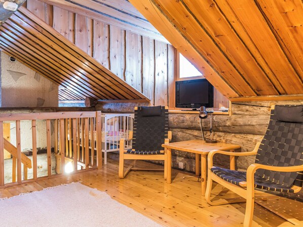 A wooden interior with a high ceiling, a television, and seating area.