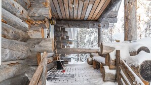 A log cabin interior with a wooden staircase leading to a snow-covered deck.