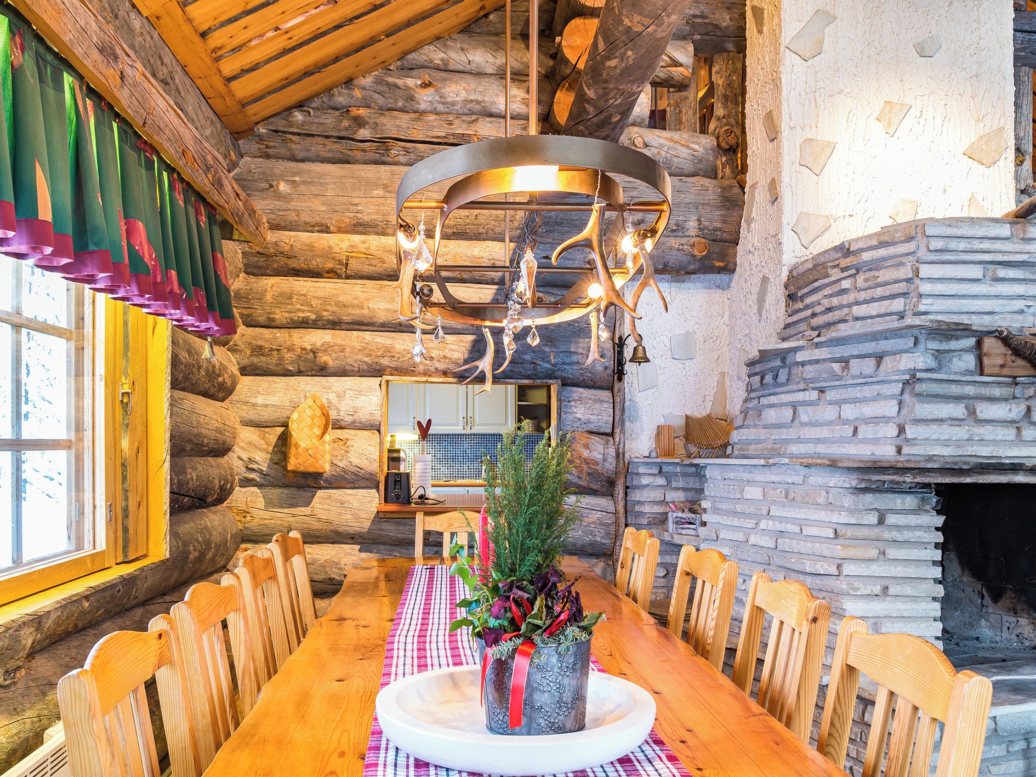 A rustic wooden interior with a dining table set for four, a fireplace, and a hanging light fixture.