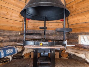 A wood-burning stove with a chimney, logs, and a sign indicating it's a Finnish sauna.