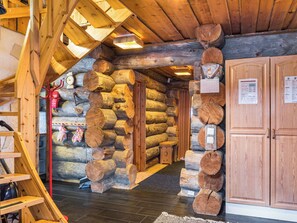 A log cabin interior with a wooden staircase, log walls, and a wooden door.