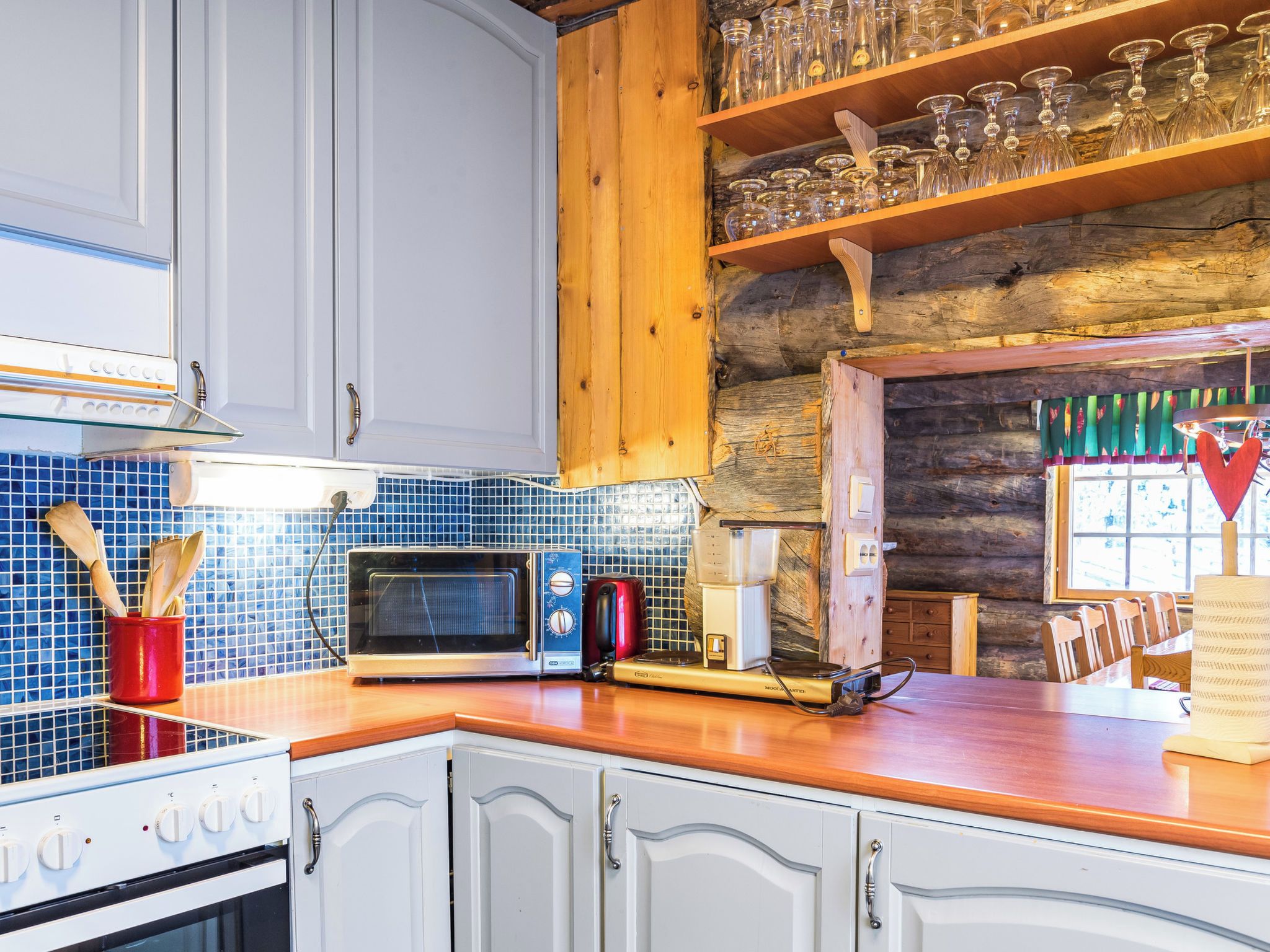 A kitchen with white cabinets, a wooden countertop, a microwave, a toaster, and a coffee maker.