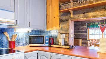 A kitchen with white cabinets, a wooden countertop, a microwave, a toaster, and a coffee maker.