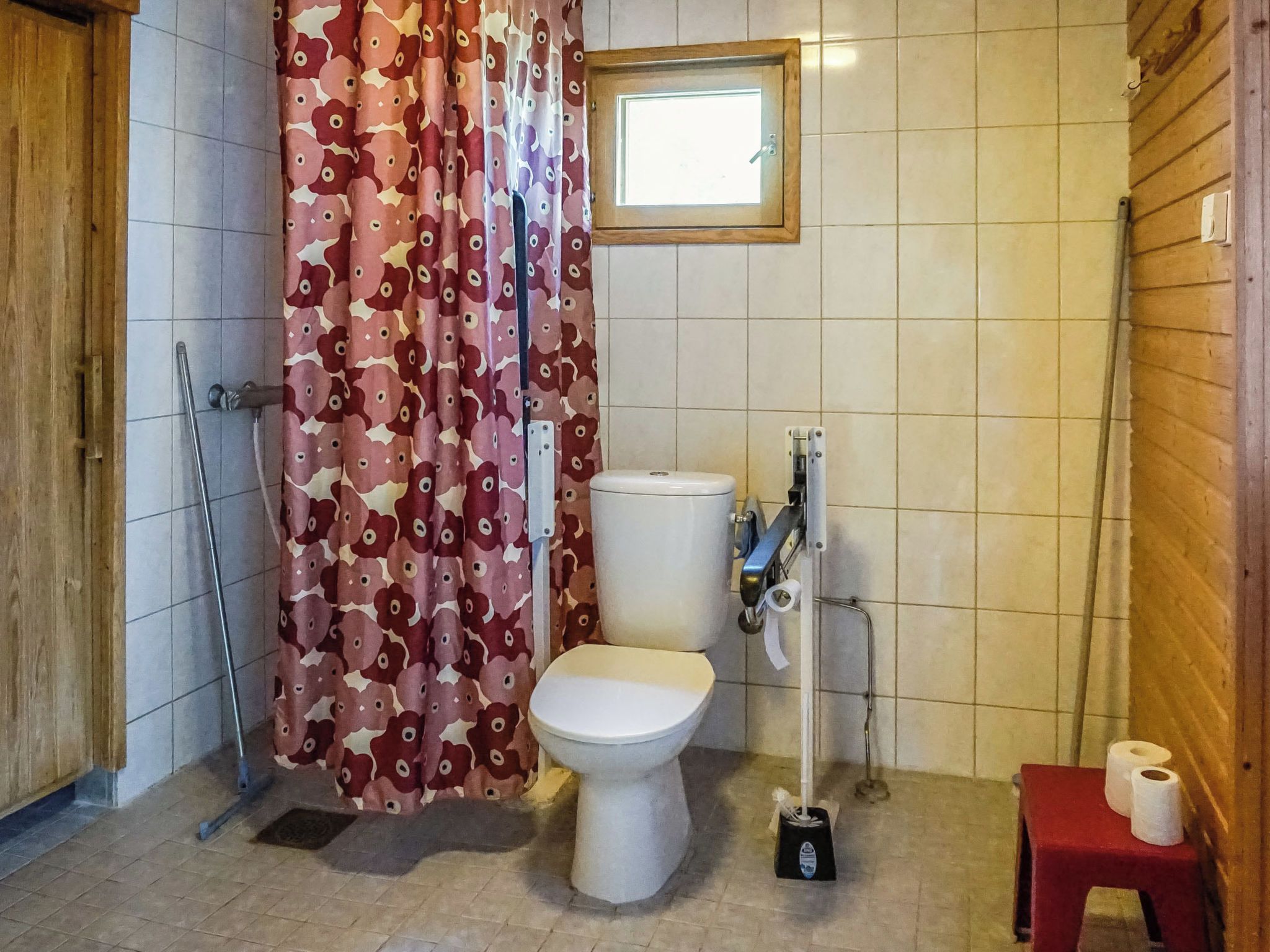 Een badkamer met toilet, douche en een klein tafeltje met toiletpapier.