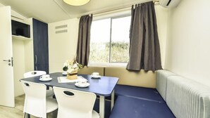A compact room with a dining table, chairs, a bench, a window with curtains, and an air conditioning unit. - Vacation home Palma by Interhome (Novigrad (Zadar))