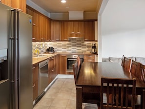 A modern kitchen with wooden cabinets, stainless steel appliances, and a dining area with a wooden table and chairs. - 4 seasons a 2 by Interhome (Sotkamo)
