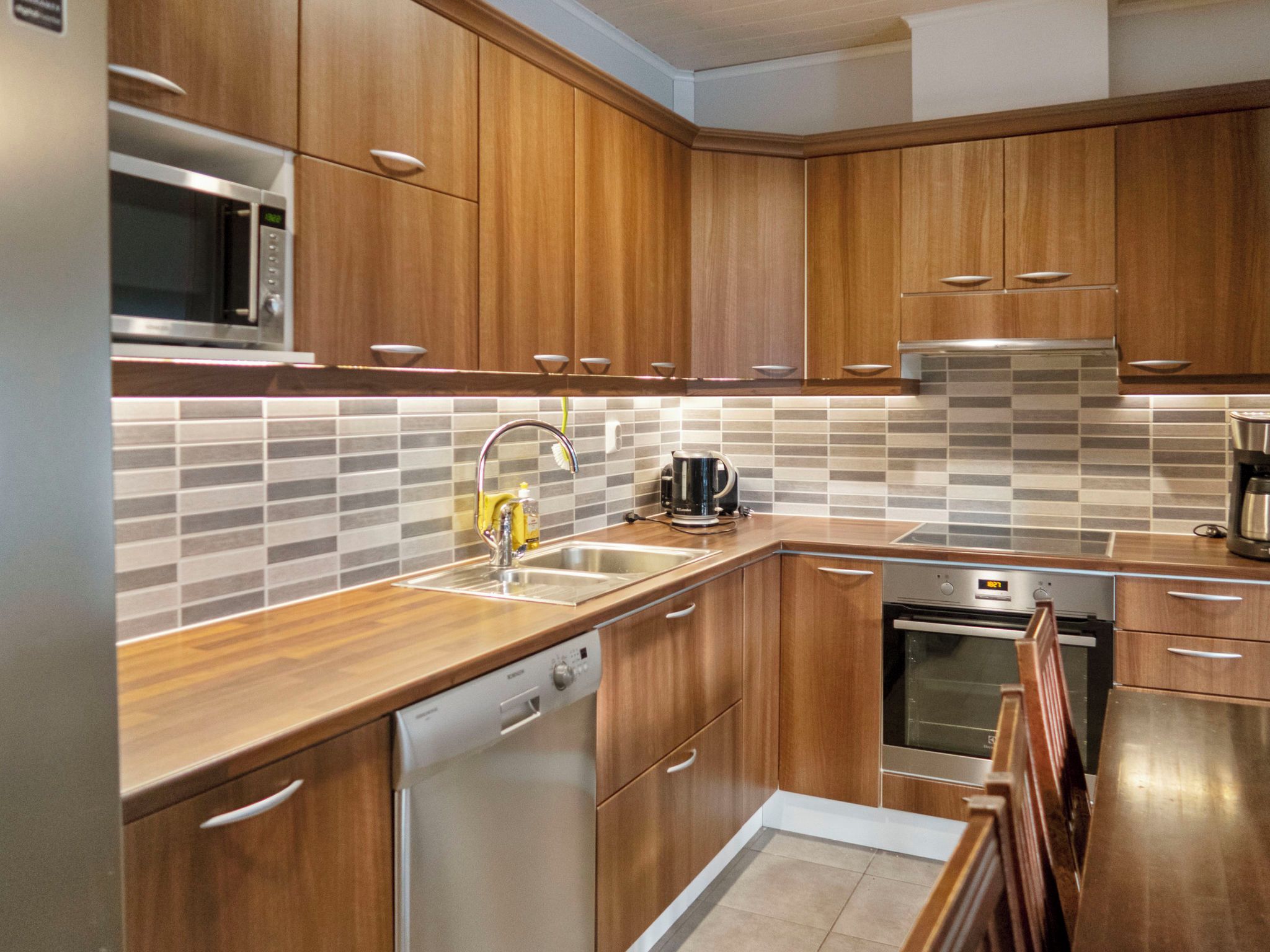 A modern kitchen with wooden cabinets, stainless steel appliances, and a tiled backsplash.