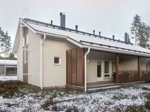 Ein eingeschossiges Gebäude mit Satteldach, einer Veranda und einem Schornstein.