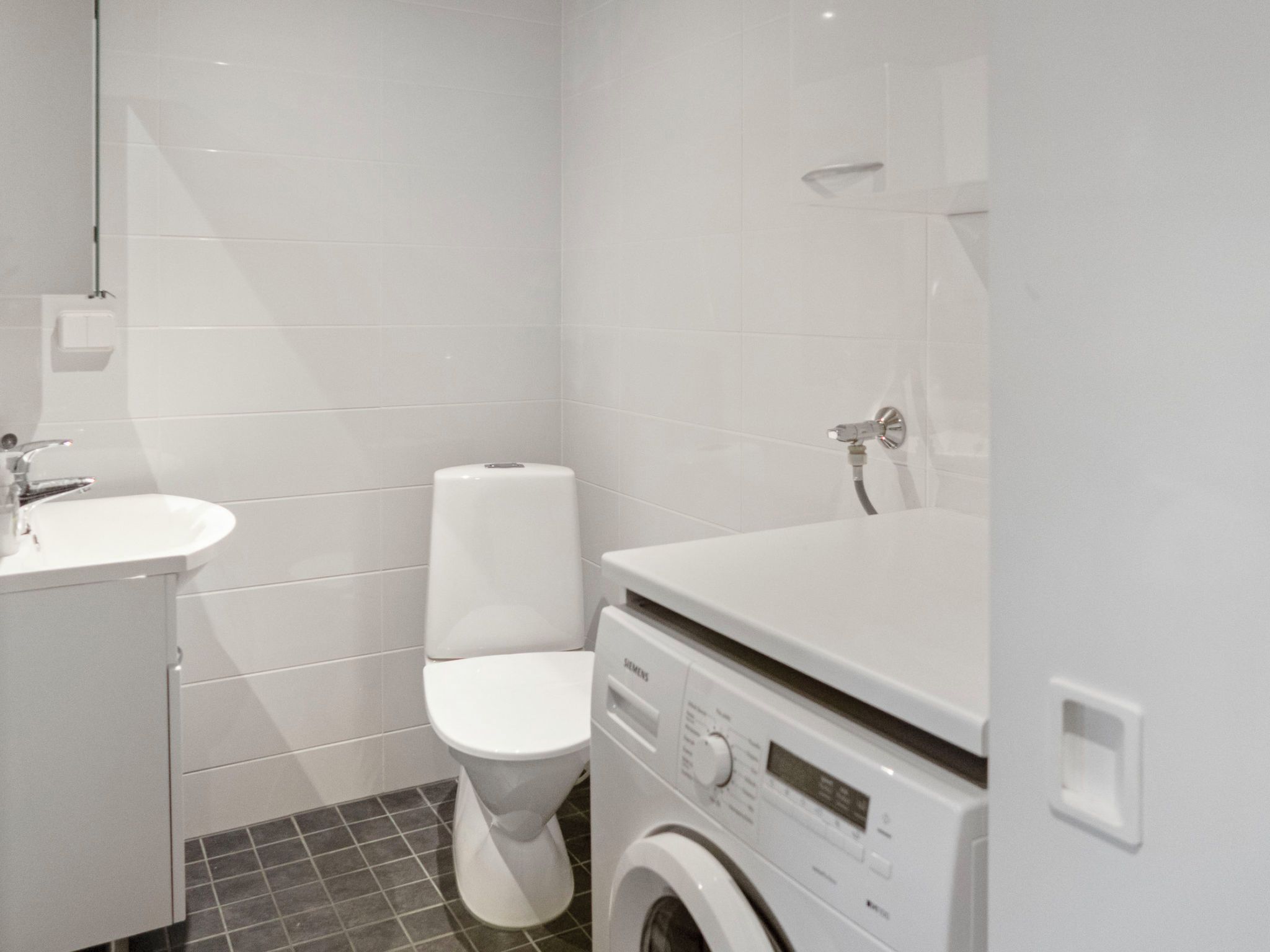A compact bathroom with a toilet, sink, and washing machine.