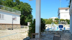 Un espace extérieur abrité comprenant une piscine, un sol en pierre et des sièges.