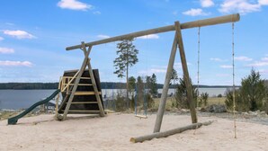 Une plage de sable avec une balançoire en bois et un toboggan.