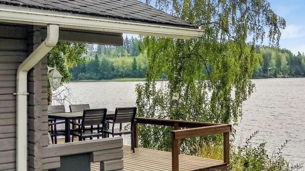 Une terrasse en bois avec des sièges extérieurs, donnant sur un lac.