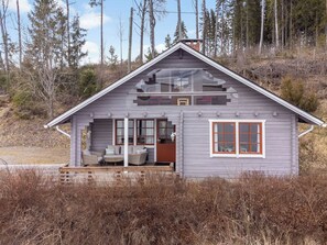 A small cabin with a porch, a dining area, and a large window.