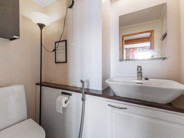 Ein Badezimmer mit Waschbecken, Spiegel, Handtuchspender und Duschkopf.