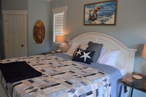 A neatly made bed with a quilt, a wall-mounted artwork, and a door. - Stunning! 4BR/3Ba - sleeps 10 - Swim Spa, Elevator and Pets Welcome (Carolina Beach)