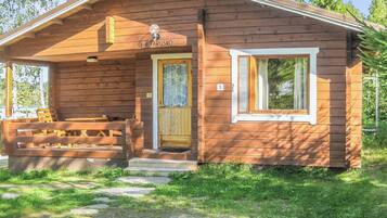 A wooden cabin with a front porch, a bench, and a door labeled 'ILTAARUSKO'.