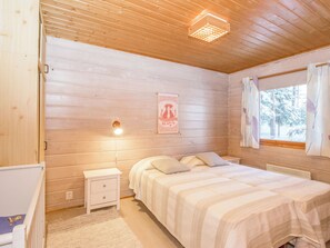 A wooden cabin bedroom with a bed, nightstand, and a poster on the wall. - Iltarusko by Interhome (Savonlinna)