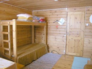Una habitación de madera con literas, una puerta y una mesita.