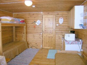 Una cabaña de madera con literas, un pequeño rincón de cocina y una puerta con un letrero.