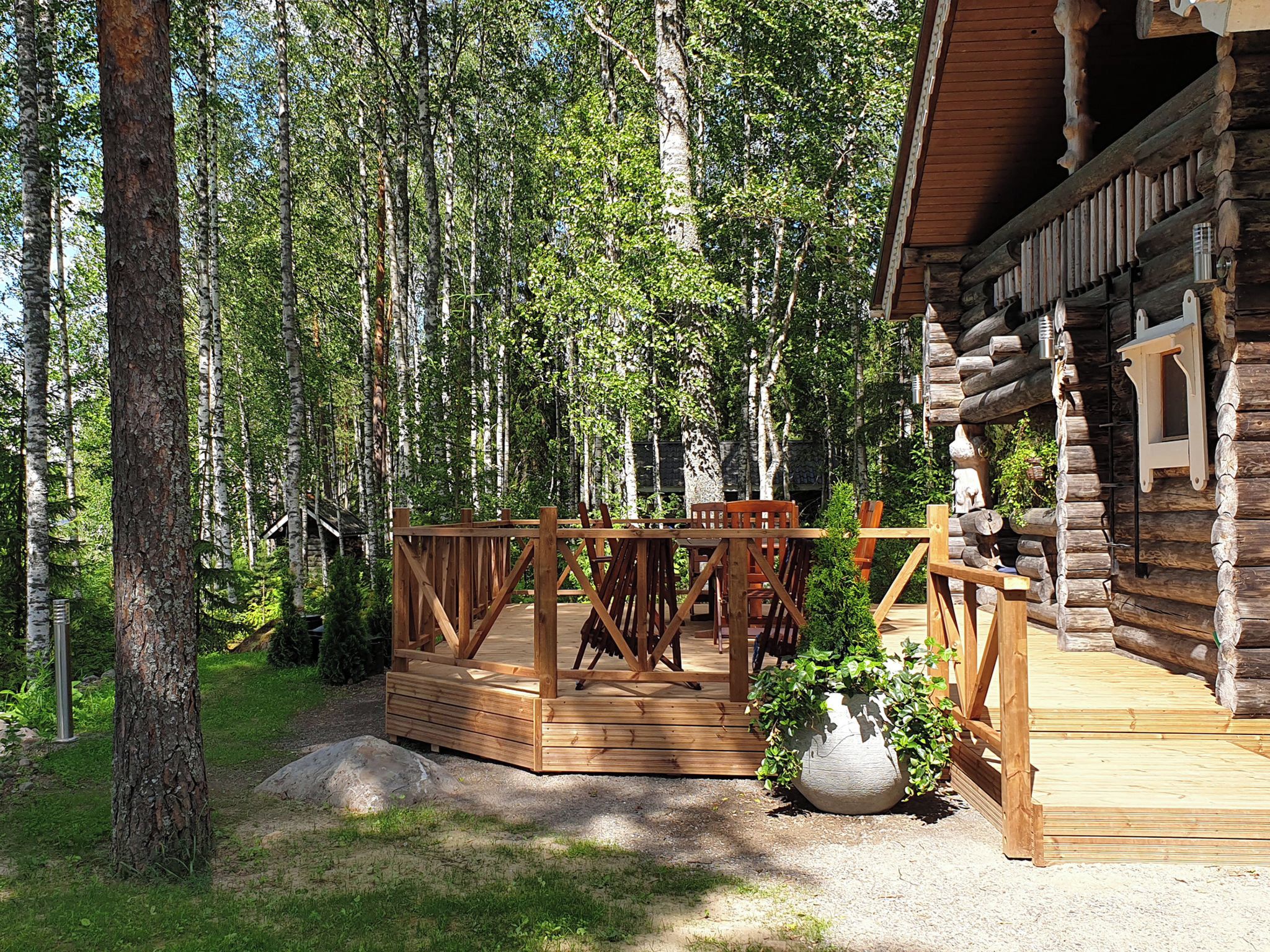 Eine Holzterrasse mit einer rustikalen Holzhütte in bewaldeter Landschaft.