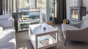 Una sala moderna con un televisor de pantalla plana, chimenea y ventanas amplias.