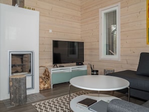 Ein modernes Wohnzimmer mit Flachbildfernseher, einer Couch, einem Couchtisch und einem Kamin.