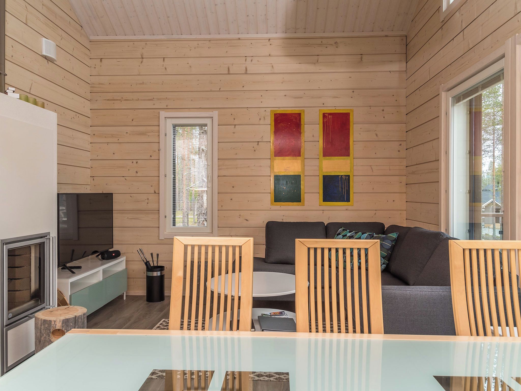 Ein modernes Interieur mit einer Holzvertäfelung an der Decke, einem Glastisch, einer Couch und einem Fernseher.