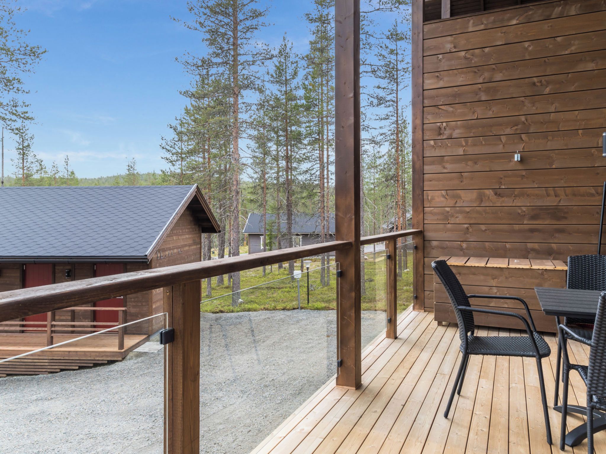 Puinen terassi, jossa on ulkokalusteita, kaide ja näkymä metsäiselle alueelle.
