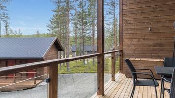 Puinen terassi, jossa on ulkokalusteita, kaide ja näkymä metsäiselle alueelle.