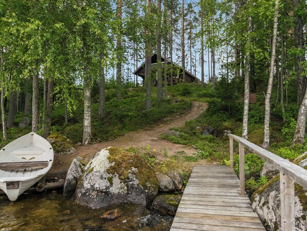 Une jetée en bois mène à un chalet rustique entouré d’une forêt.