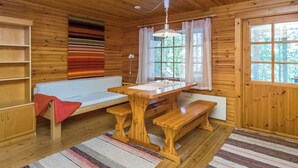 L’intérieur d’un chalet accueillant, avec un plafond en bois, un banc, une table et une fenêtre agrémentée de rideaux.