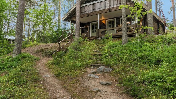 Un chalet rustique avec une façade en bois, une véranda et un escalier menant à l’entrée.