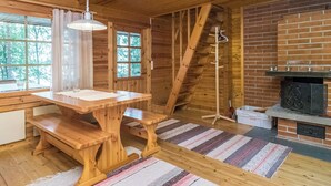 L’intérieur d’un chalet en bois comprend une table à manger, des bancs, une cheminée et un escalier.
