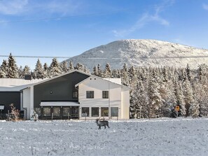 Un bâtiment moderne doté d’une grande entrée et ayant une montagne en toile de fond.