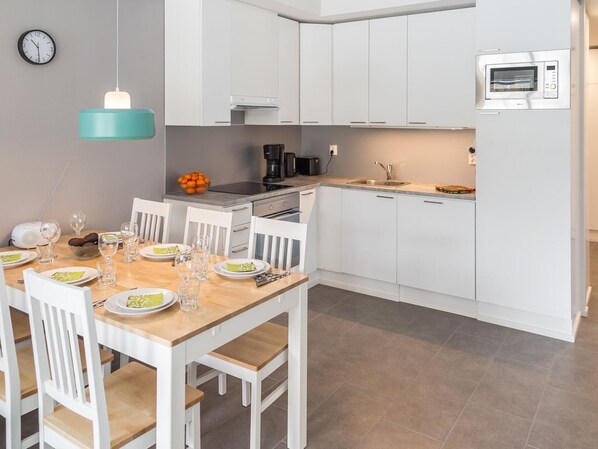 Een koelkast, een magnetron, een vaatwasser, kookgerei, borden en bestek